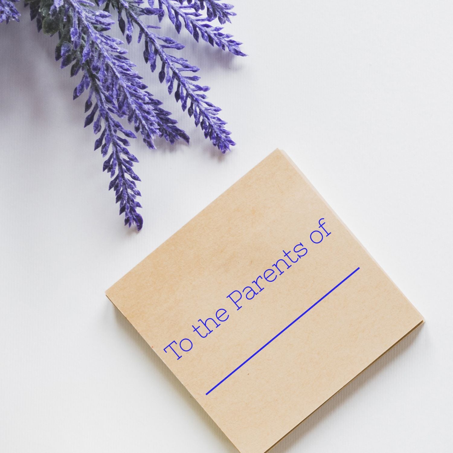 Event invitation card made of kraft paper with blue lettering and purple feather accents on a clean white background, top-down view.