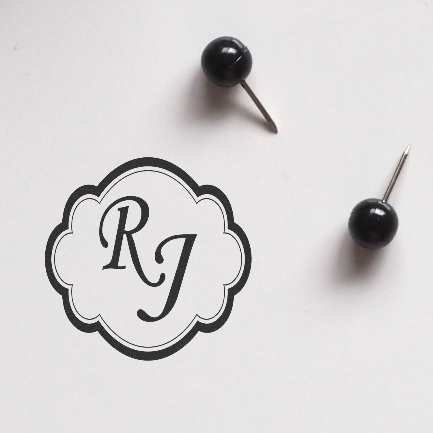 Custom monogram rubber stamp design with RJ initials in a scalloped decorative frame.
