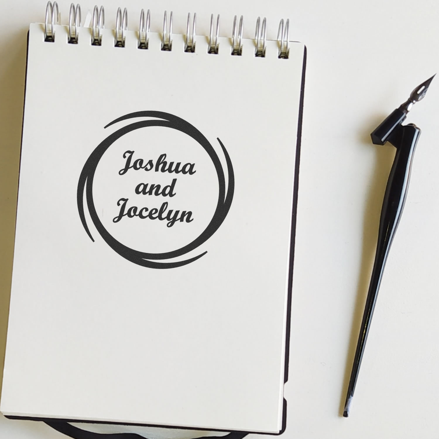 Personalized rubber stamp with Joshua and Jocelyn name design, shown on a notebook beside a fountain pen.