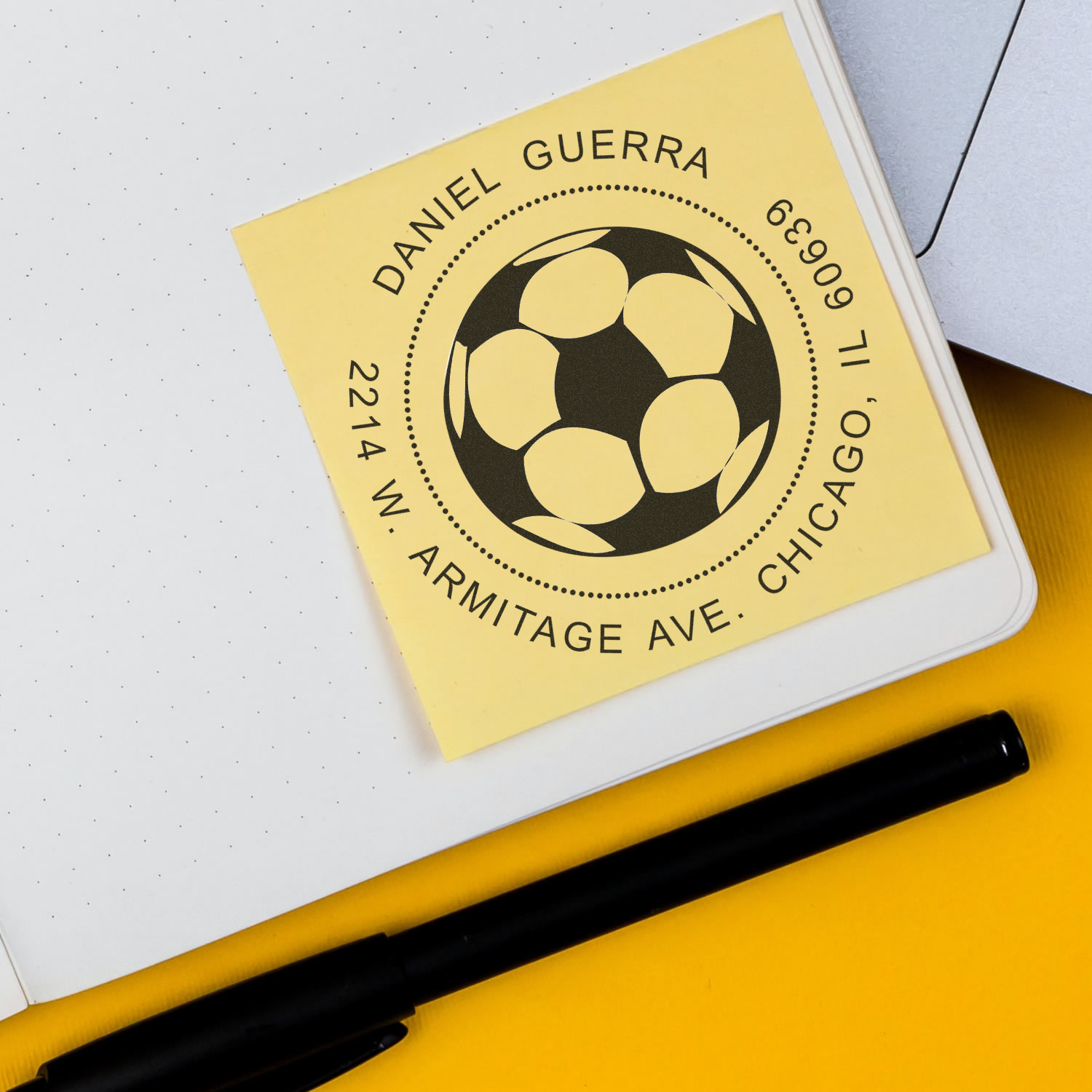 Yellow soccer badge card featuring Daniel Guerra, Armitage Ave Chicago IL 60614 address and football emblem on desk, with pen.
