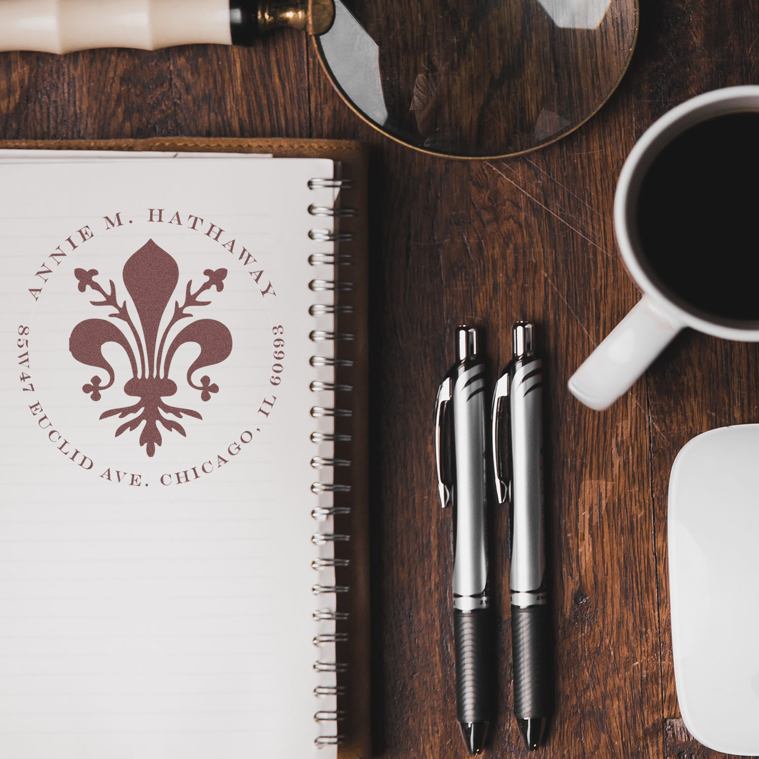 Custom return address rubber stamp with fleur-de-lis monogram on notebook, ideal for personalized stationery branding