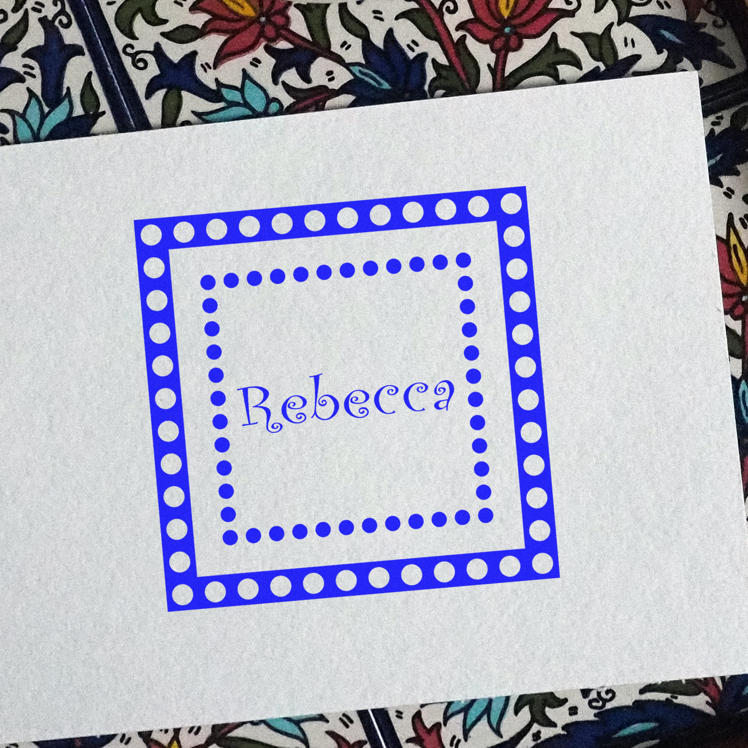 Custom rubber stamp impression with the name Rebecca in a dotted square frame, ideal for personalized stationery and crafting.