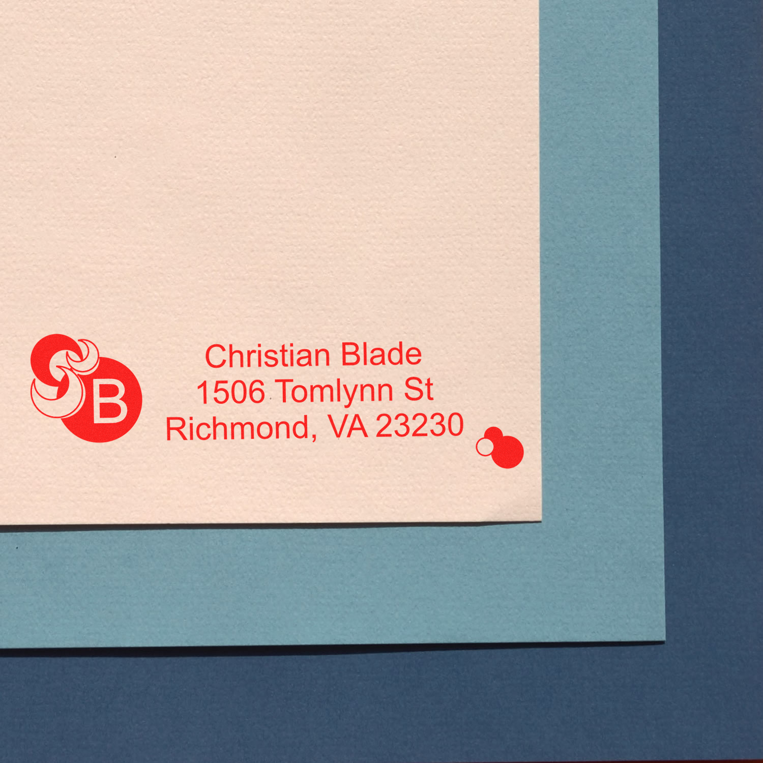 Custom red rubber address stamp with monogram on cream envelope, ideal for personalized stationery and business mail.