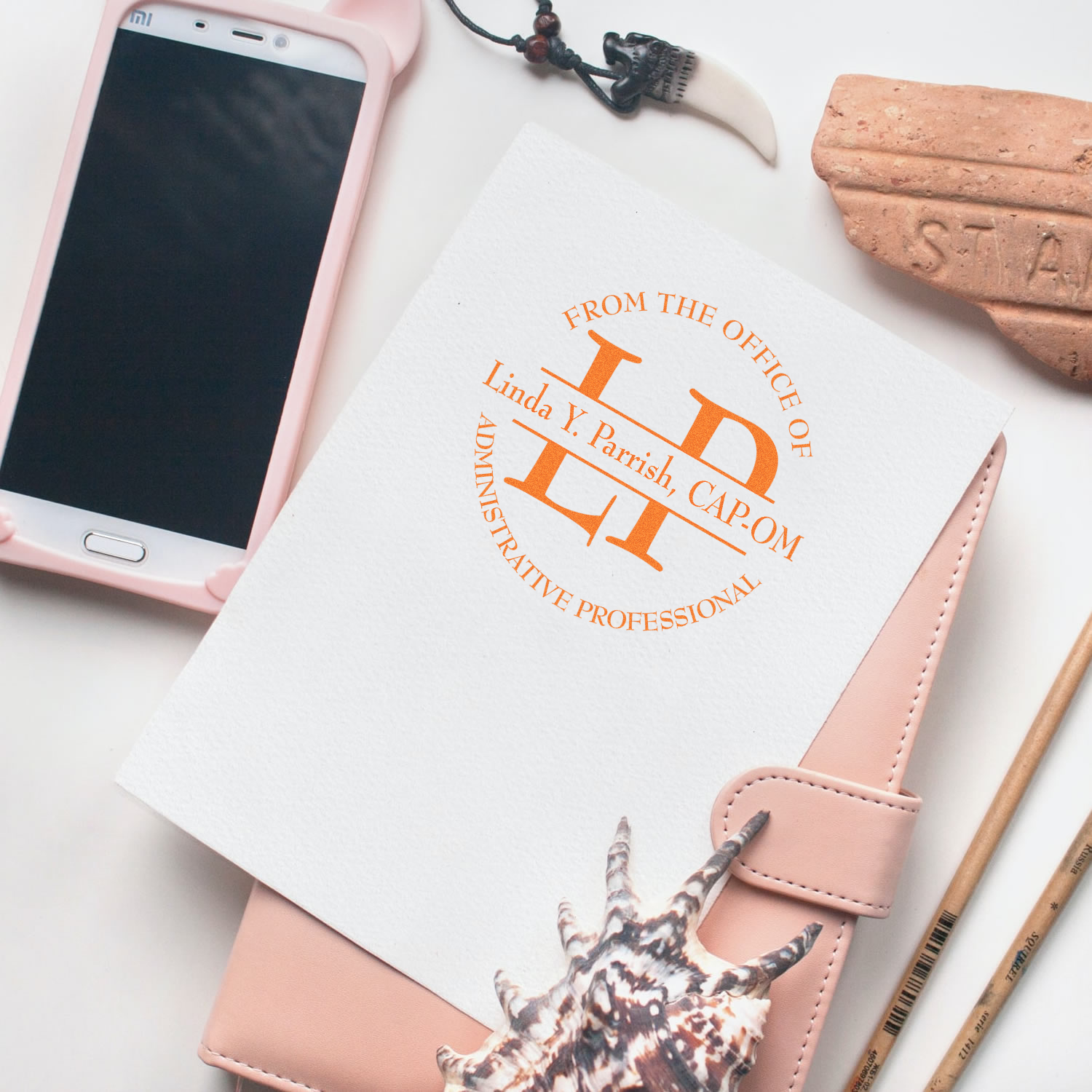 Custom rubber stamp on notebook, featuring personalized administrative professional branding for office stationery.