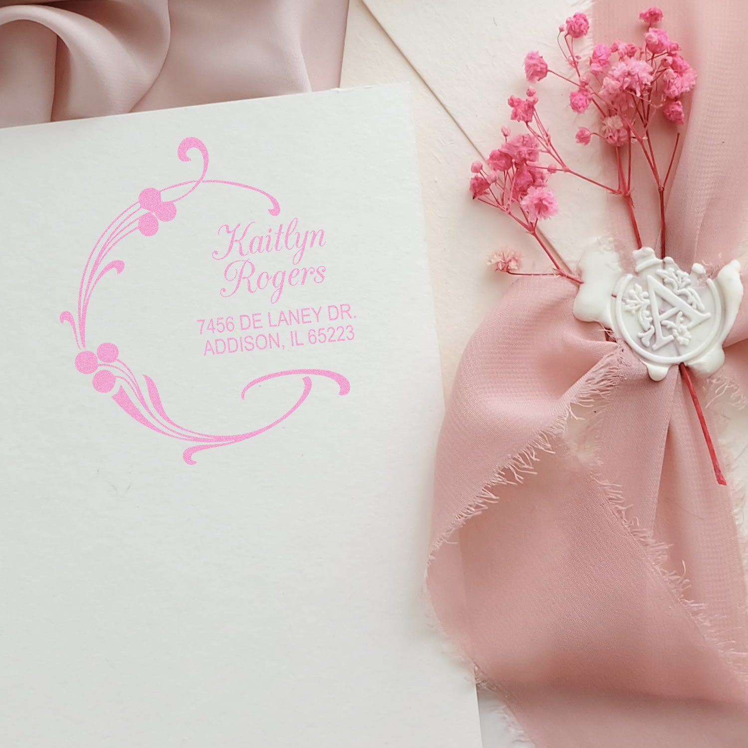 Custom floral return address rubber stamp with pink monogram and name on wedding envelope, styled with blush ribbon and flowers