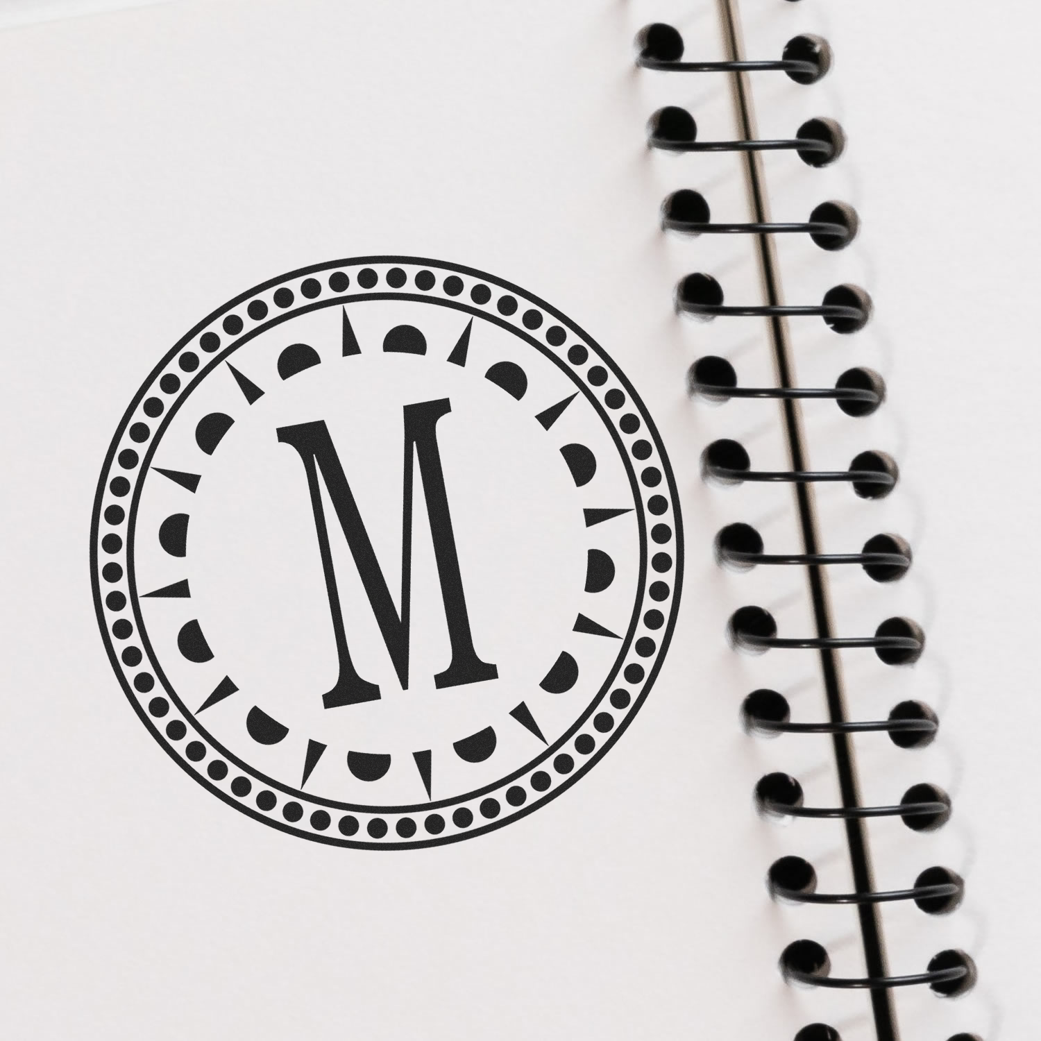 Custom monogram rubber stamp with letter M stamped on a notebook page for personalized branding