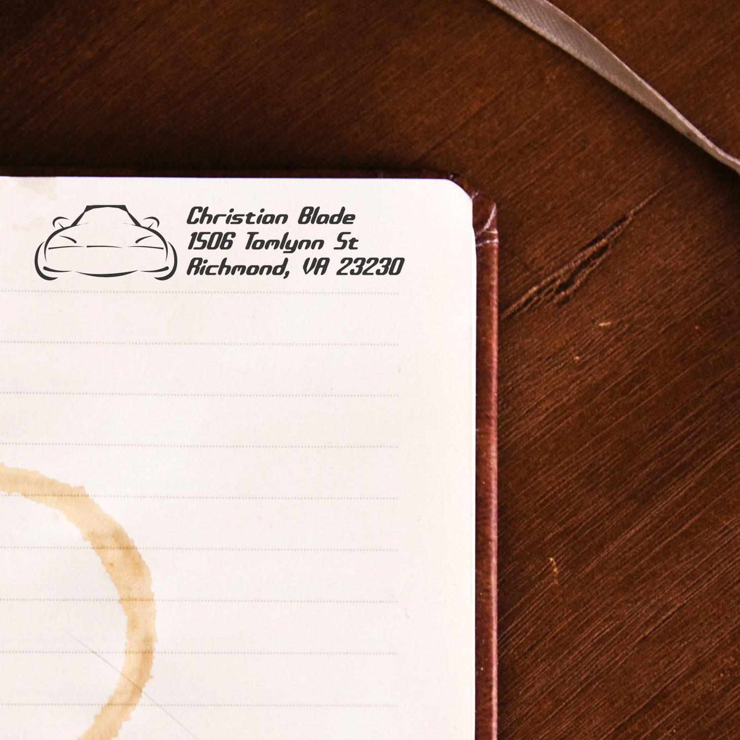 Custom rubber address stamp on notebook page with car logo, name, and Richmond, VA address imprint.