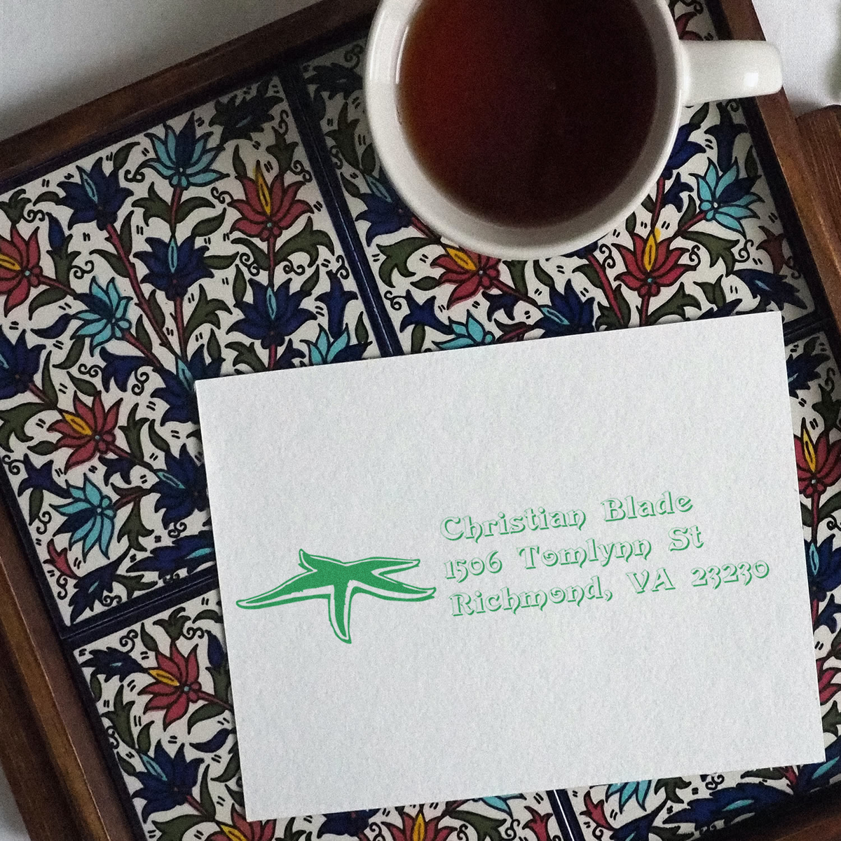 Custom rubber stamp return address on stationery, with green ink imprint beside a coffee cup for personalized mailings.