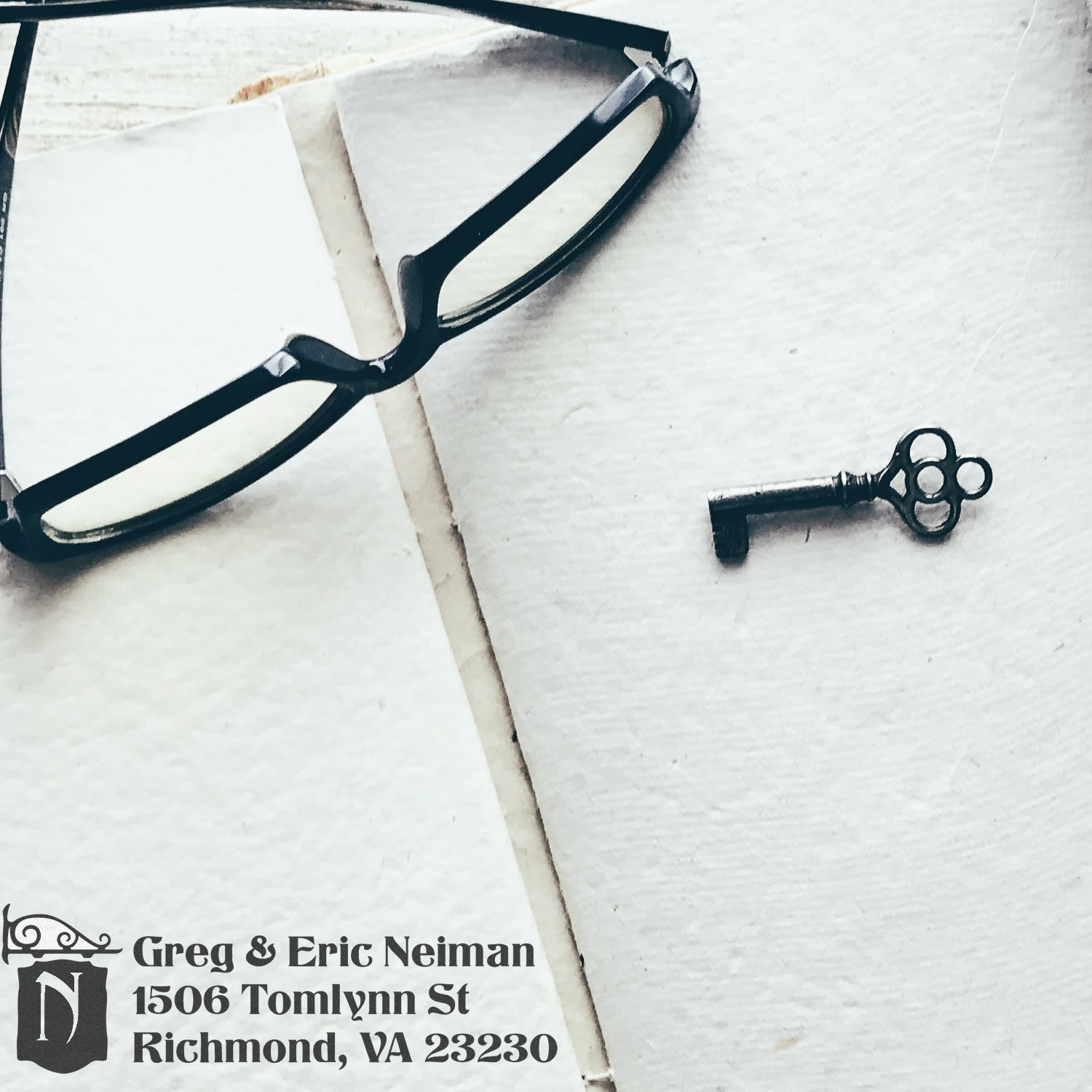 Custom return address rubber stamp on paper, with eyeglasses and key, showing Greg & Eric Neiman, Richmond, VA.