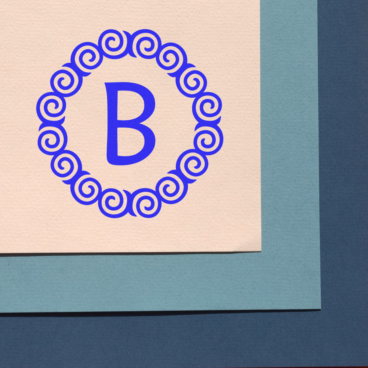 Blue decorative letter B monogram in ornate circle on greeting card cover, branding design.