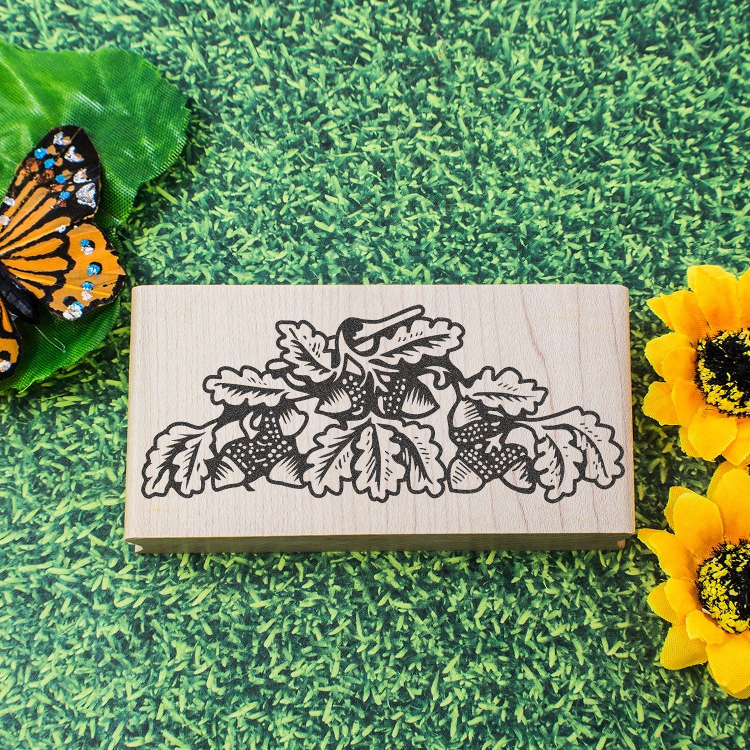 Wooden floral leaf stamp with butterfly and sunflower decor on green grass background