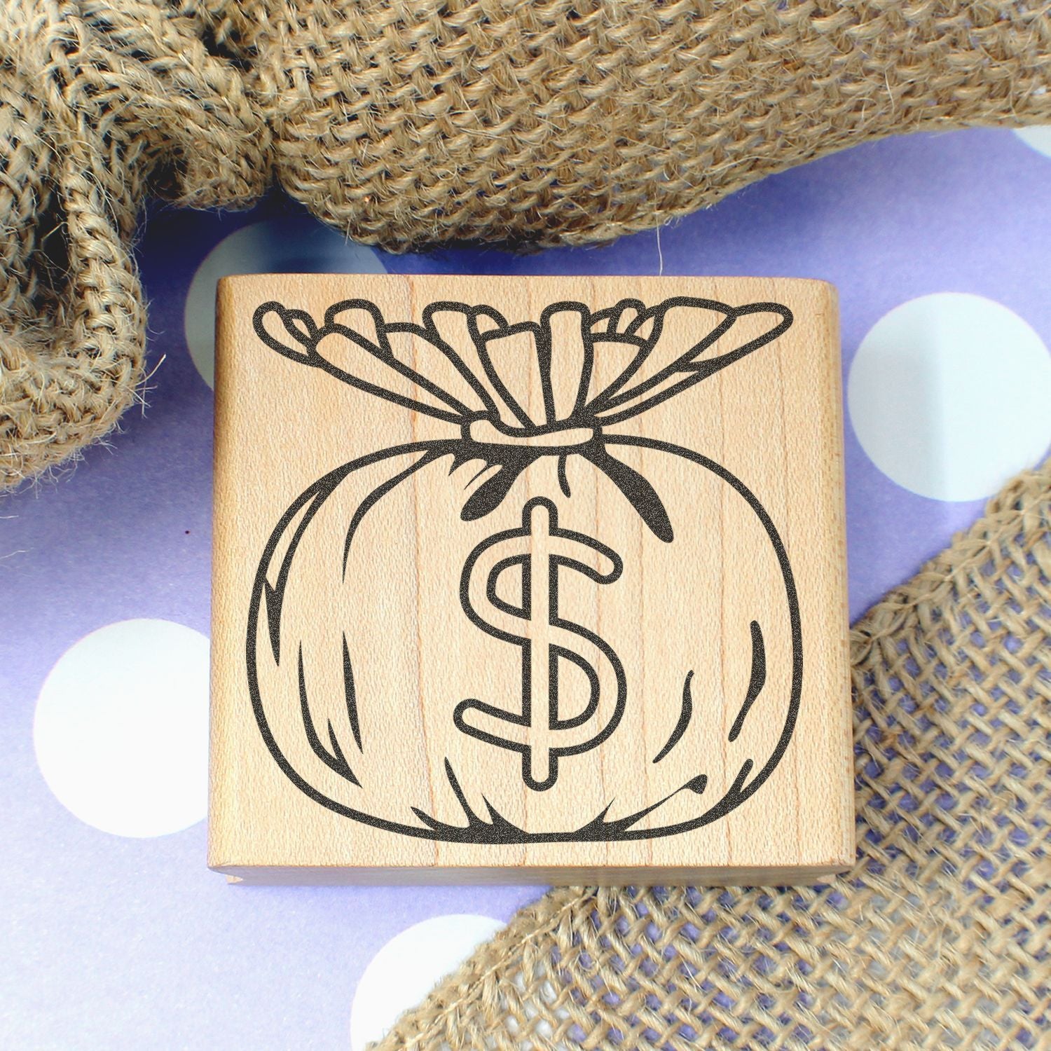 Wooden money bag stamp with dollar sign icon on burlap background, ideal for finance and savings branding.