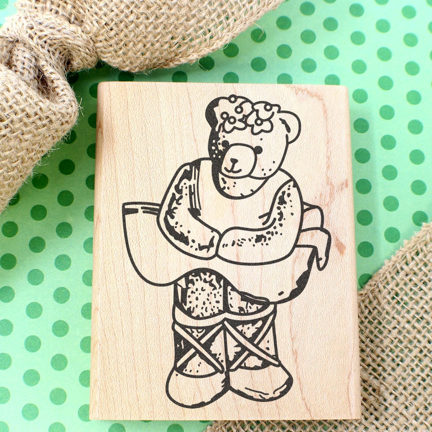 Wooden bear stamp with floral crown on green polka dot background, rustic handmade craft design.