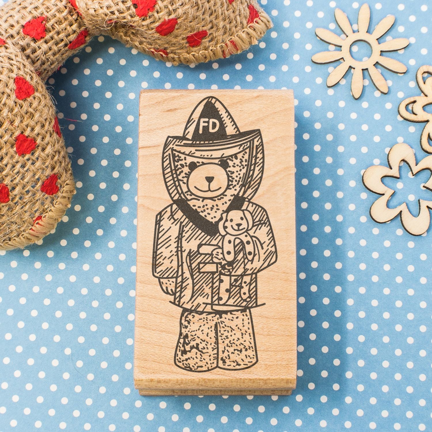 Wooden firefighter bear stamp with teddy bear design on a blue polka dot background, rustic craft decor.