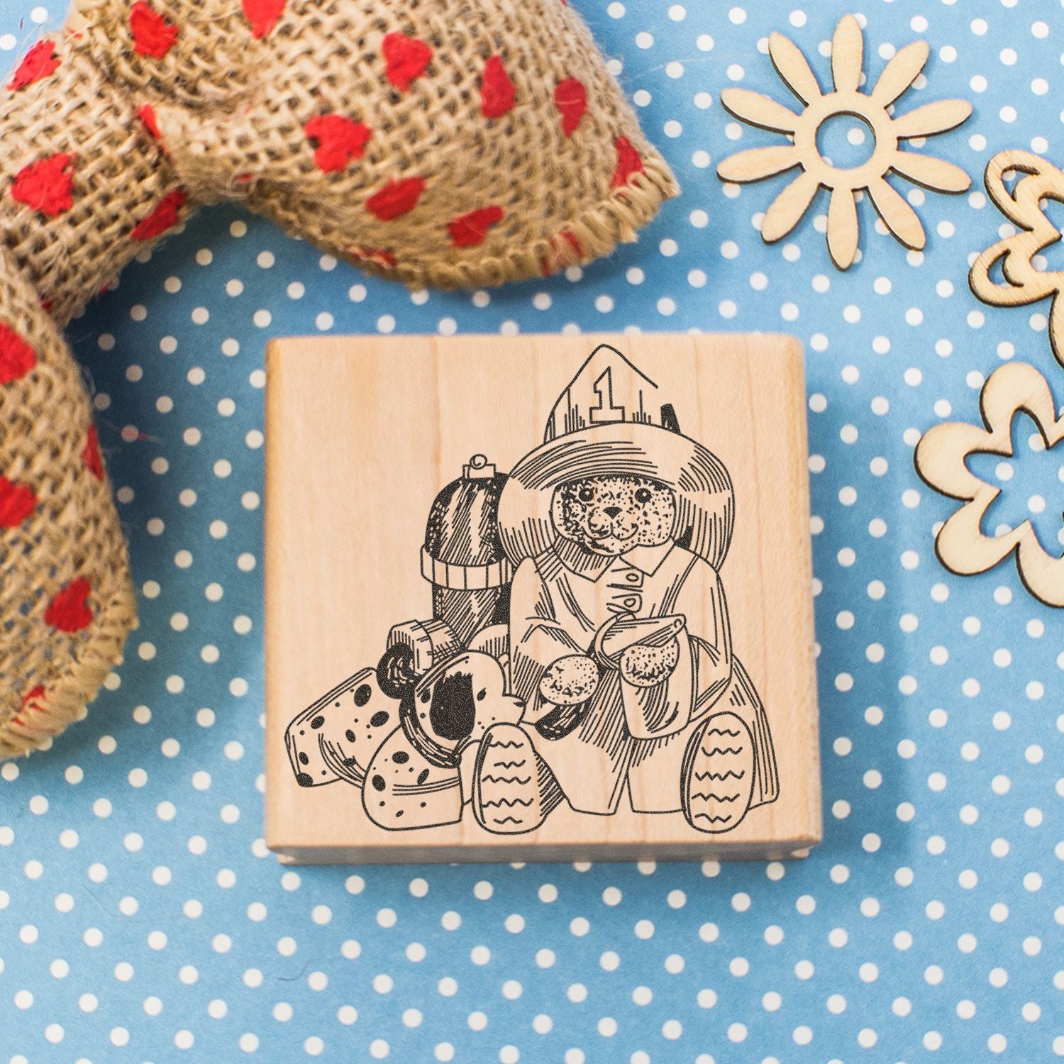 Wooden rubber stamp with a cute dog illustration, on a blue polka dot background with craft supplies.
