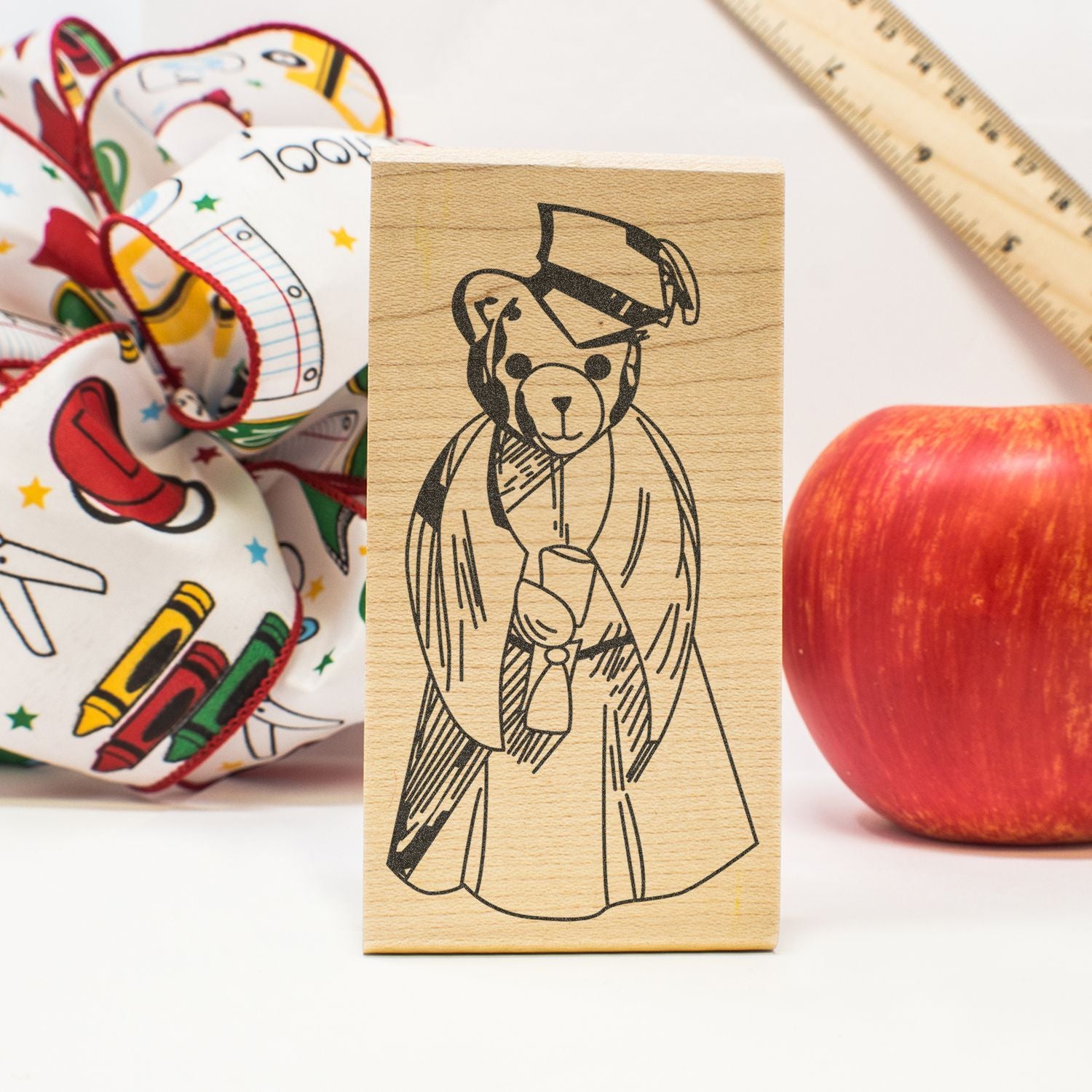 Wooden teddy bear graduation stamp with school supplies, apple, and ruler for back-to-school crafting and teacher projects
