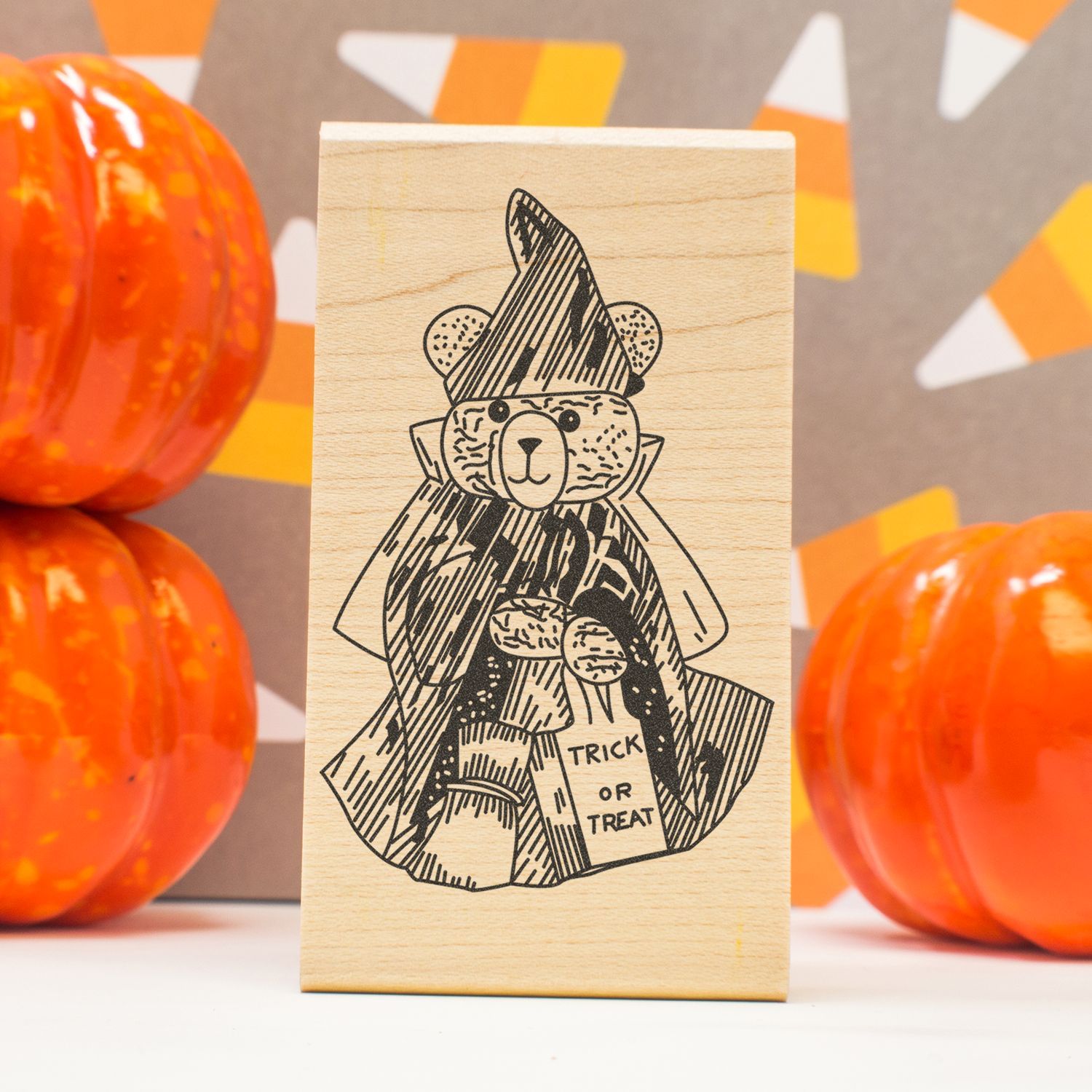 Halloween teddy bear wooden stamp with trick-or-treat bag and pumpkins on a festive autumn background