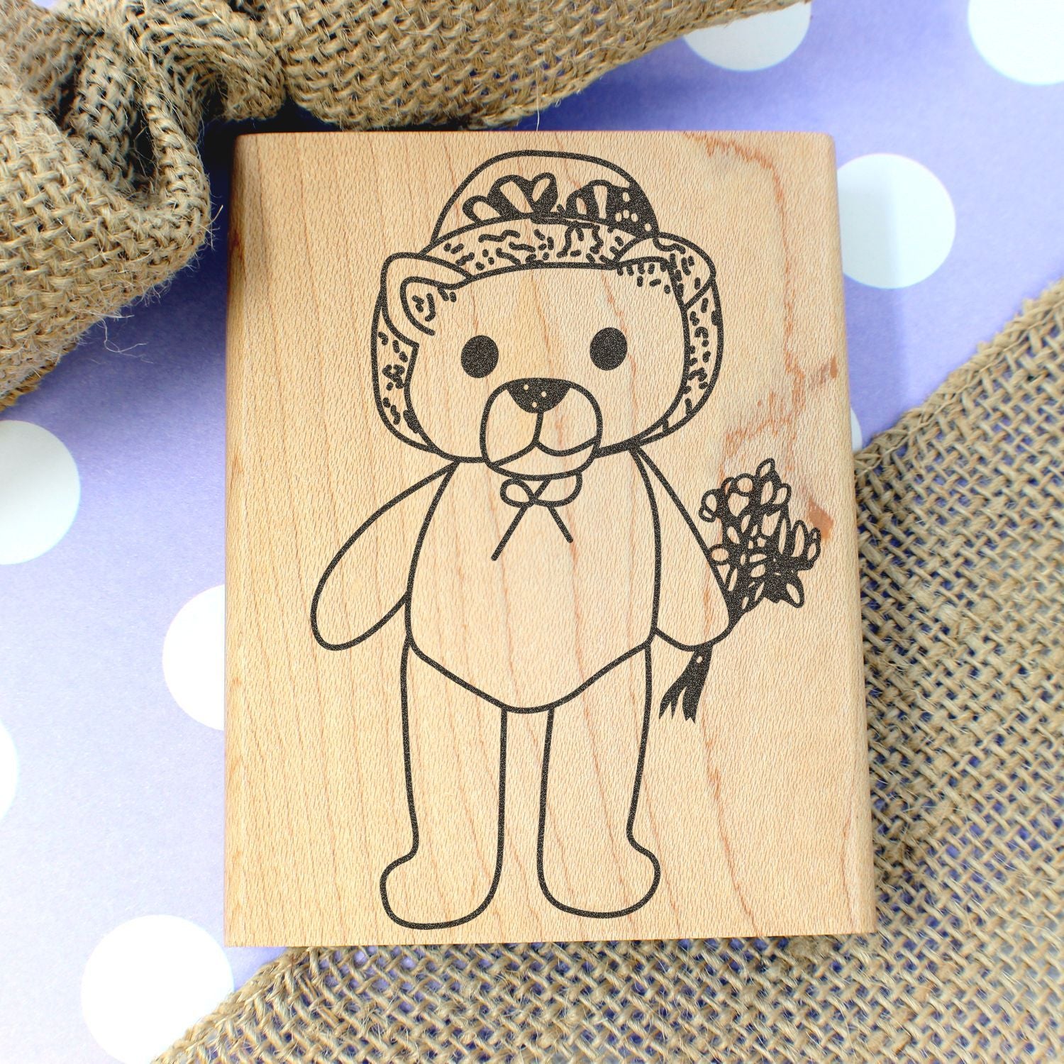 Wooden teddy bear stamp with floral crown on rustic burlap and polka dot background, cute nursery decor and handmade craft design