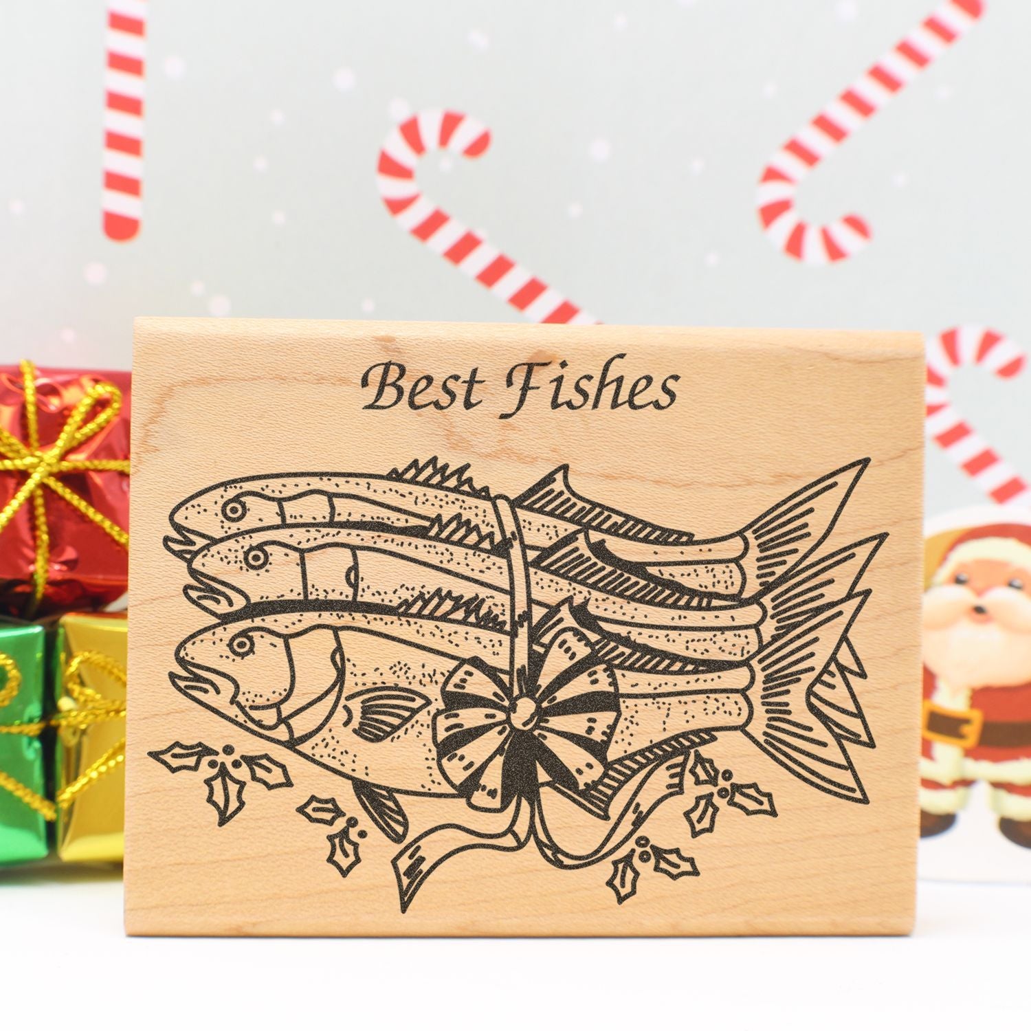 Wooden Best Fishes holiday sign with engraved fish illustration, Christmas gifts, and festive candy cane background.