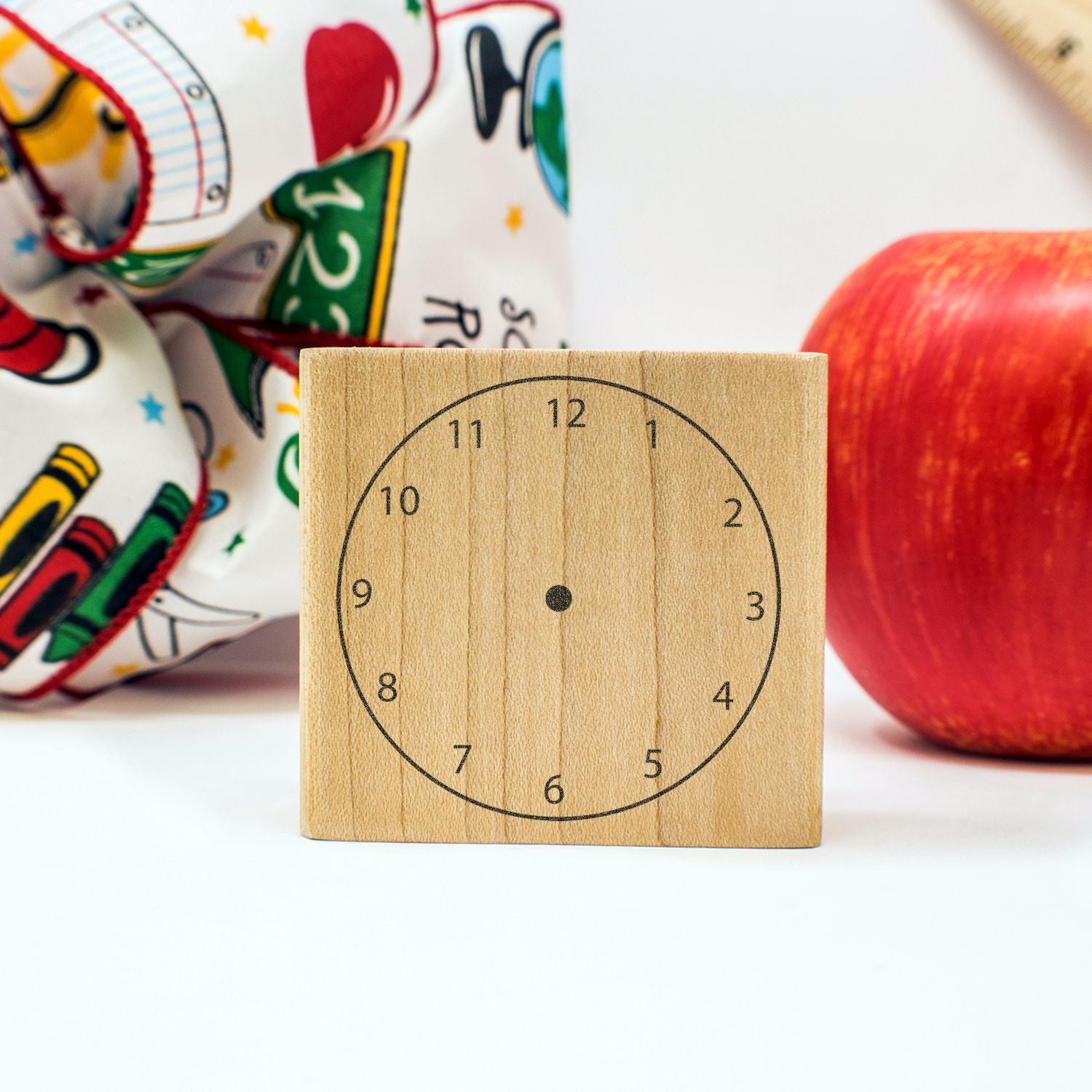 Wooden learning clock toy with numbers, apple, and school supplies on a white background.