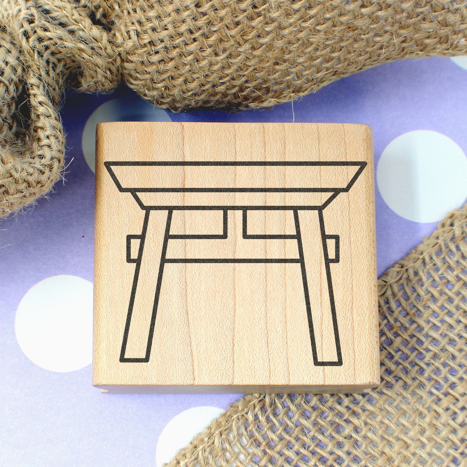 Wooden stamp with Japanese torii gate design on burlap background