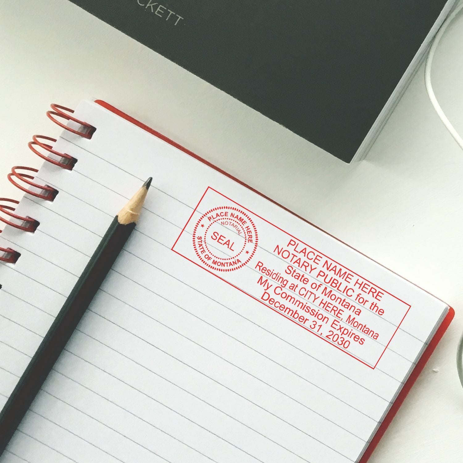 Notary public stamp on open notebook with pencil on office desk, legal paperwork concept, Montana notary seal template.