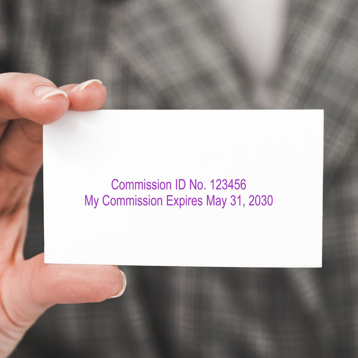 Hand holding a notary commission ID card with expiration date May 31, 2030.