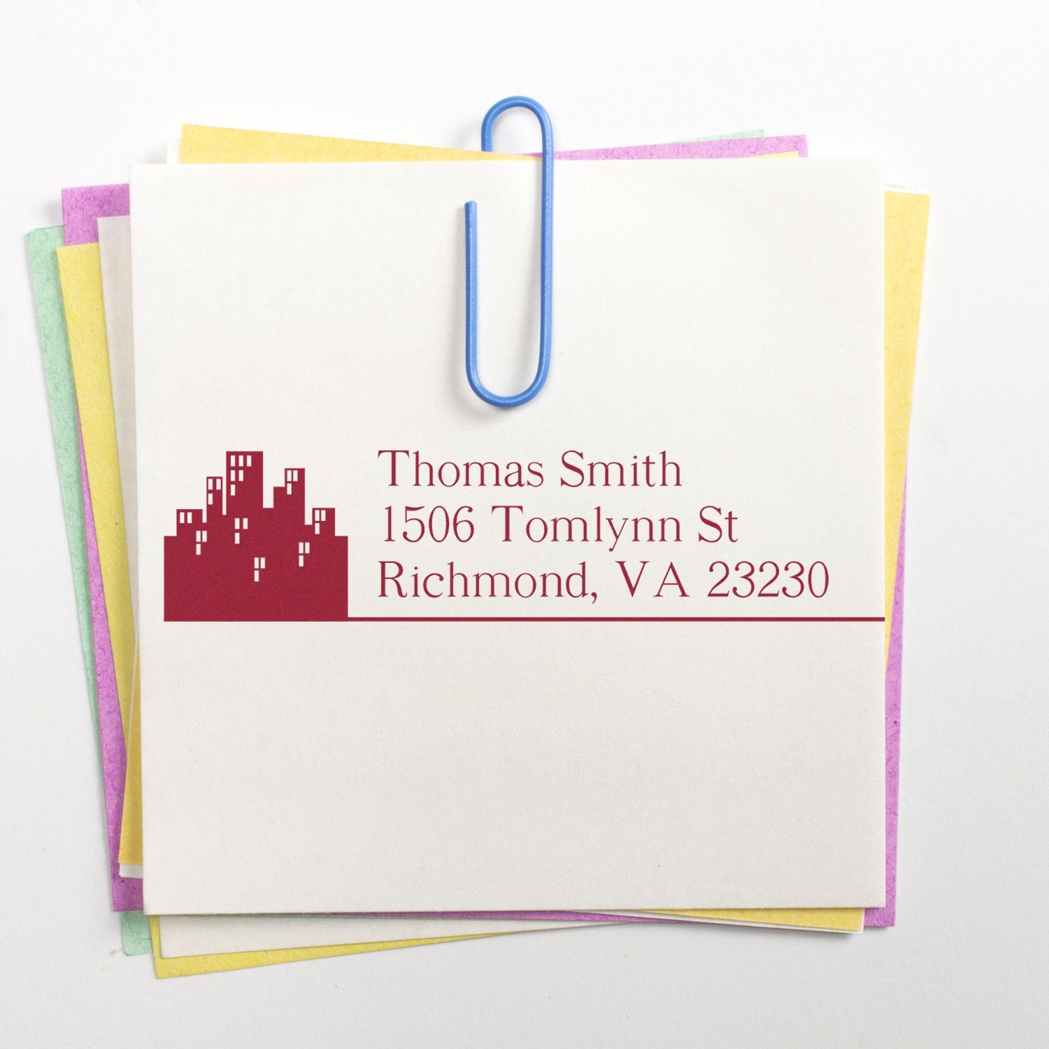 Custom return address rubber stamp with skyline logo on stacked stationery, ideal for personalized mail and business branding.