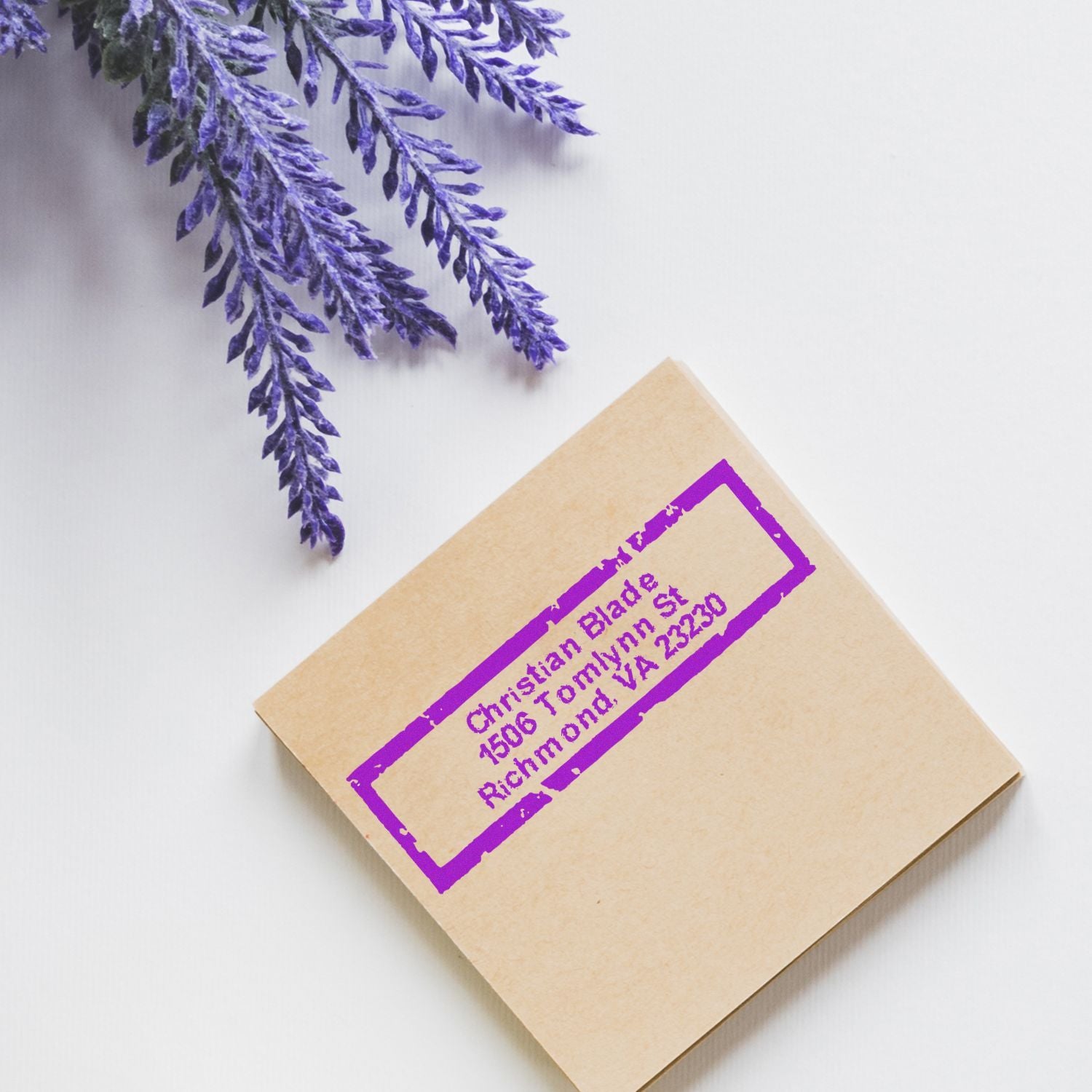 Custom purple address rubber stamp on kraft envelope with lavender sprigs, ideal for wedding or business mailings.