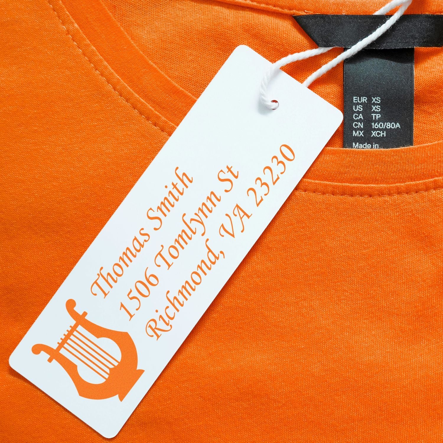 Custom rubber stamp style apparel hang tag on orange T-shirt with Thomas Smith address and logo.