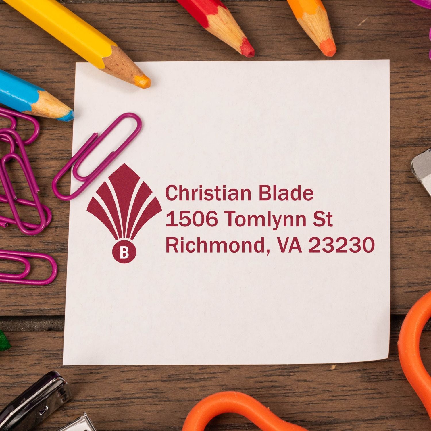 Custom return address rubber stamp for Christian Blade, Richmond VA, displayed on paper with pencils and paper clips.