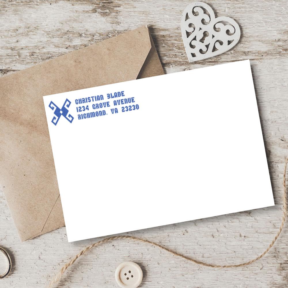 Custom return address rubber stamp on white envelope with blue ink, showing personalized address stationery for mailing.