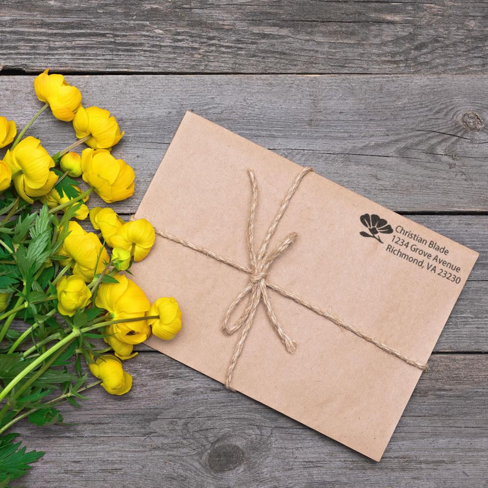 Custom return address rubber stamp on kraft envelope with twine and yellow flowers for elegant mailing.
