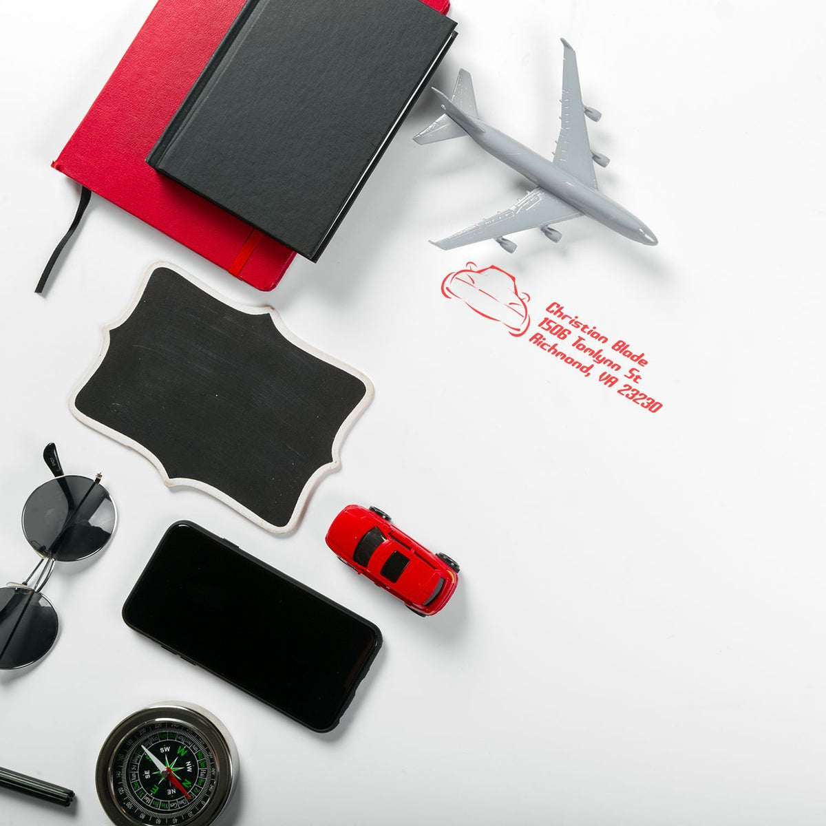 Custom rubber address stamp imprint beside travel accessories and airplane, ideal for business mailing and branding.