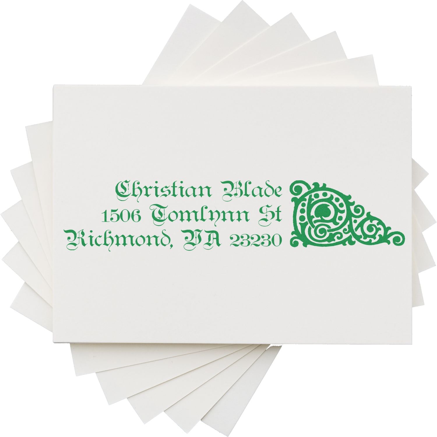 Custom return address rubber stamp with ornate monogram, name, and address printed in green on sample cards.