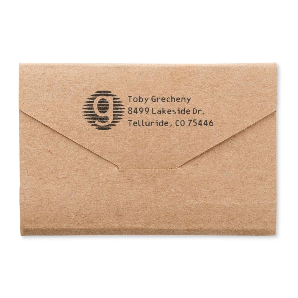Custom address rubber stamp on kraft envelope for return mailing, featuring name, street address, city, and ZIP code.