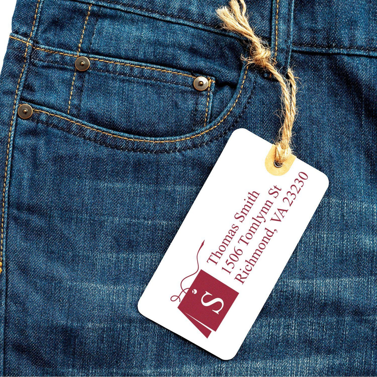 Custom rubber stamp design on apparel tag hanging from denim jeans, ideal for clothing brand labeling and packaging.