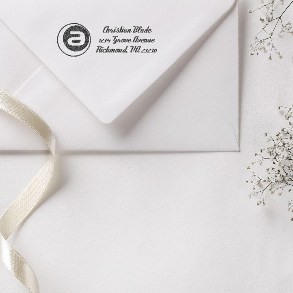Custom return address rubber stamp on white envelope with monogram logo, perfect for personalized wedding stationery.