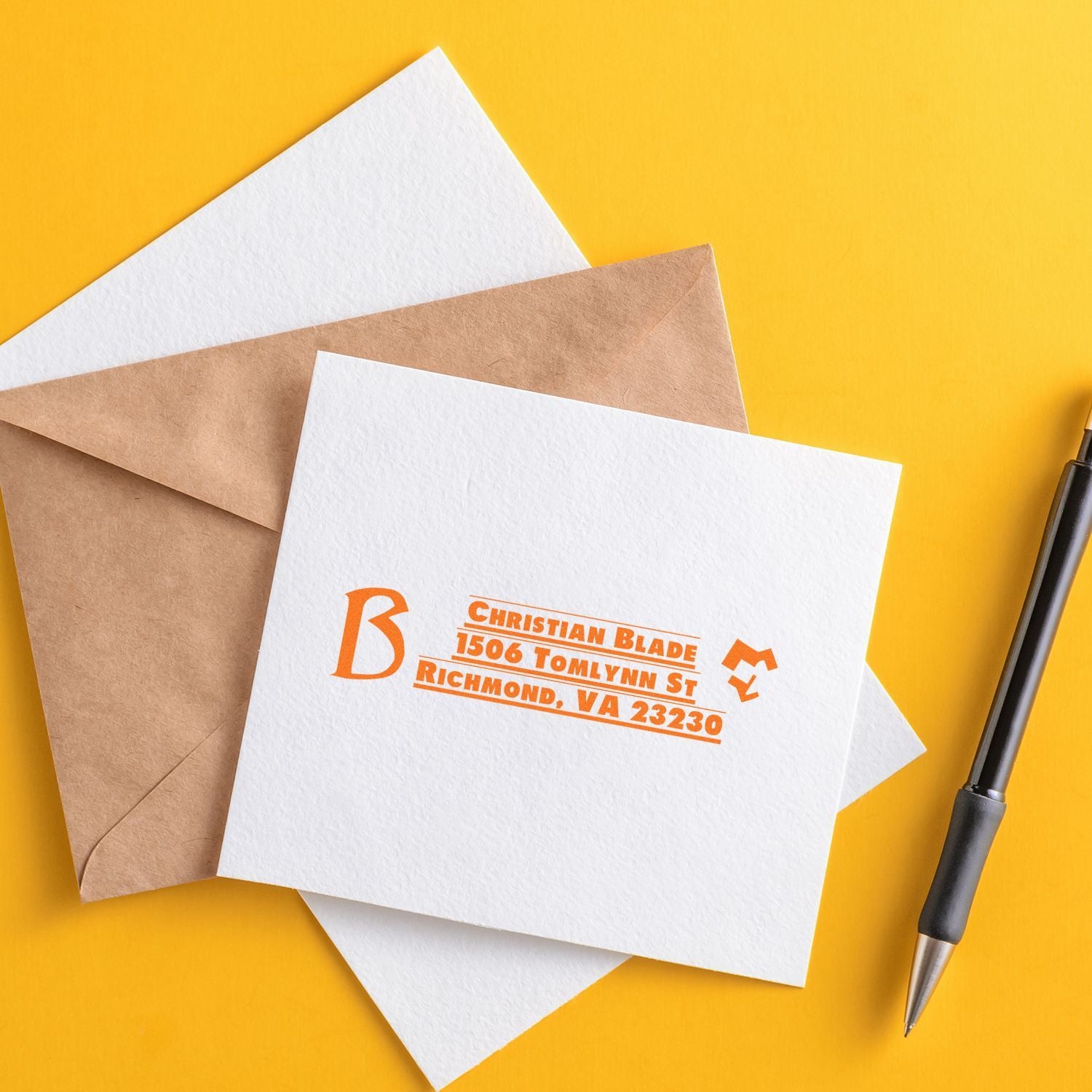 Custom return address rubber stamp on envelopes and stationery with pen, ideal for personalized mail branding.