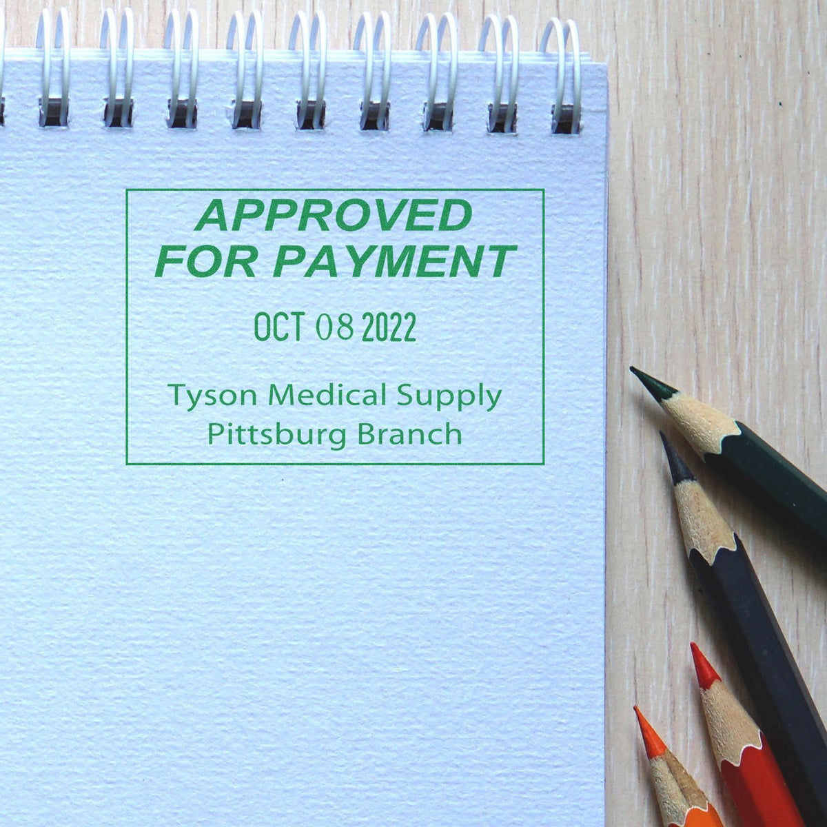 Approved for payment stamp on spiral notebook beside colored pencils, Tyson Medical Supply branch.