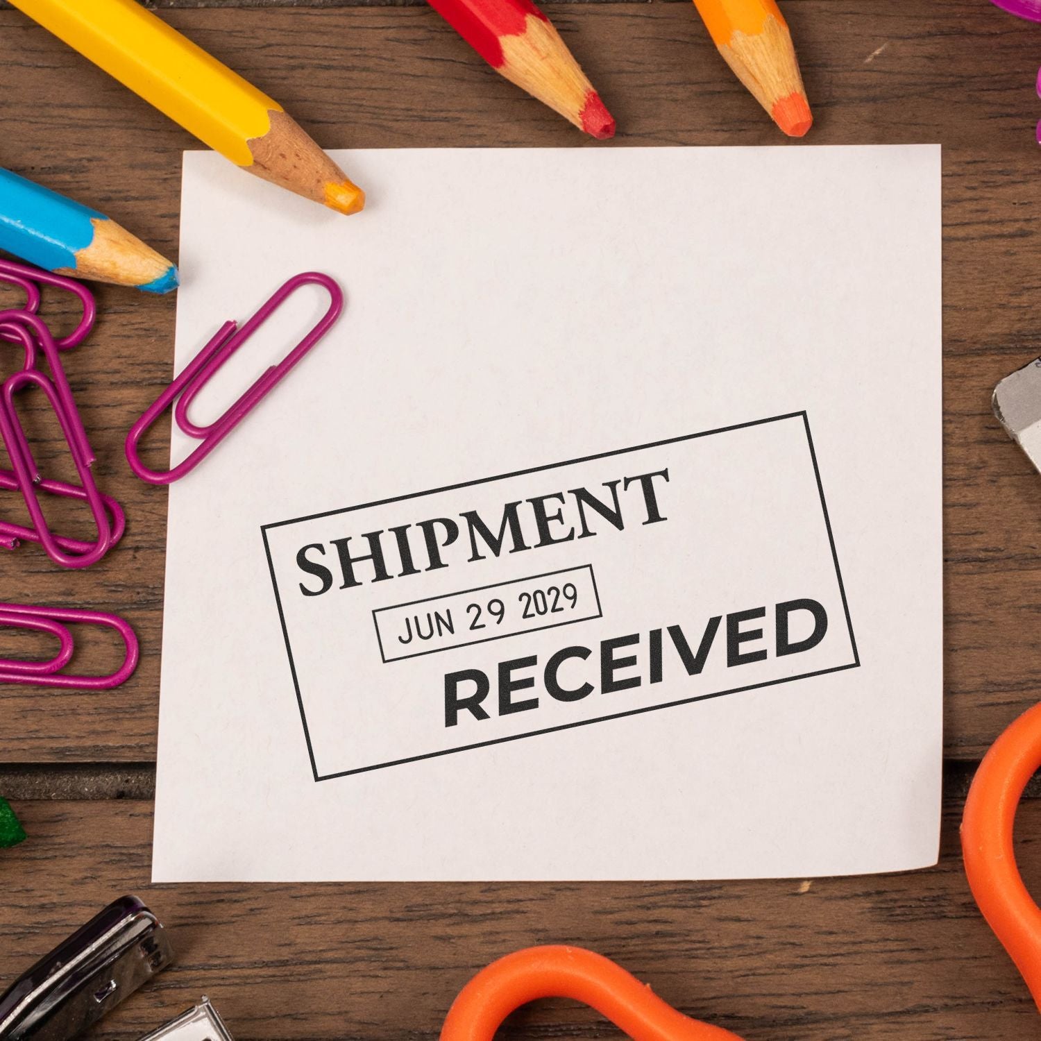 Shipment received stamp on paper with colorful pencils and paper clips on a wooden desk, office supply flat lay.