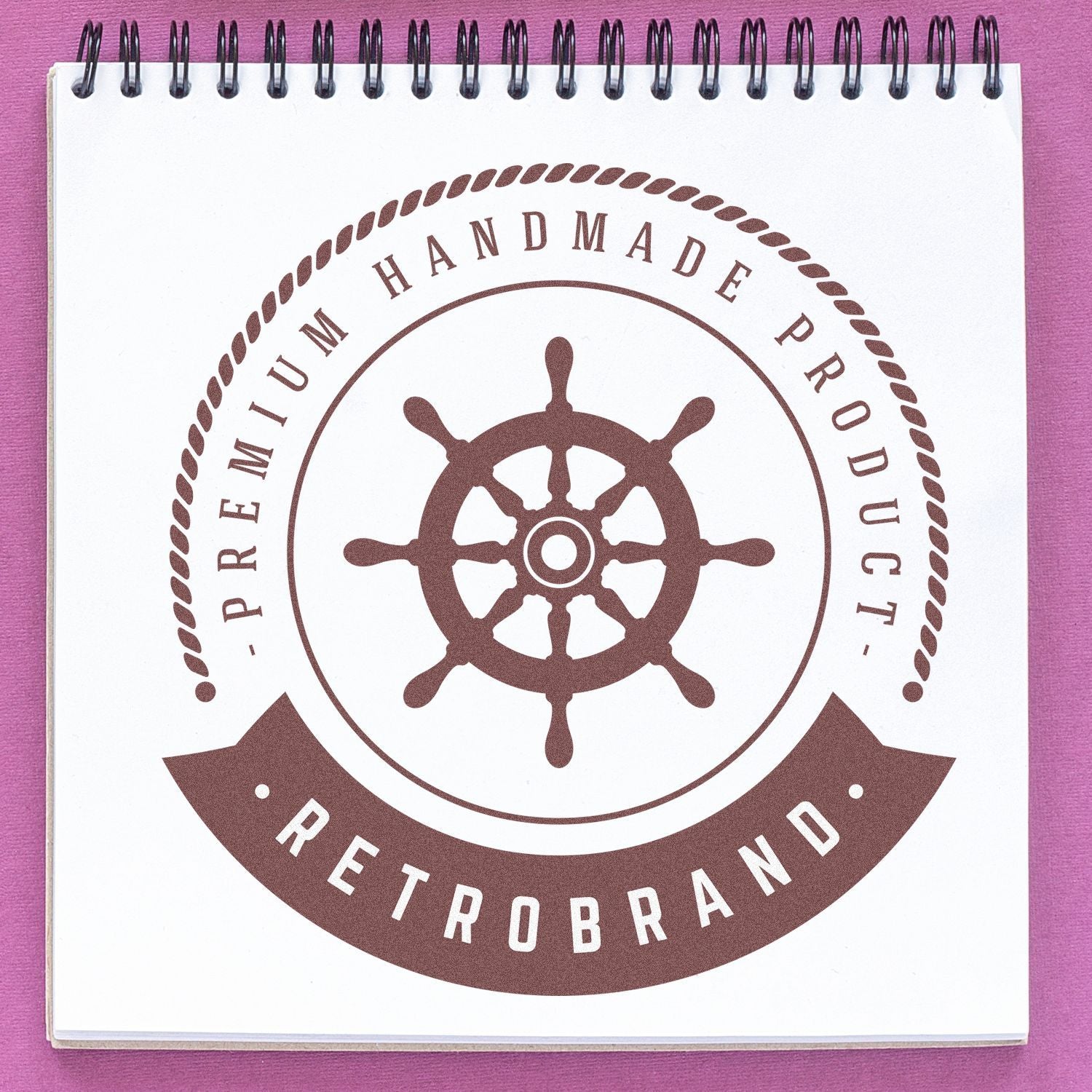 Spiral notebook cover with nautical ship-wheel logo and FREITROBRAND text, retail branding for handmade product wrapping