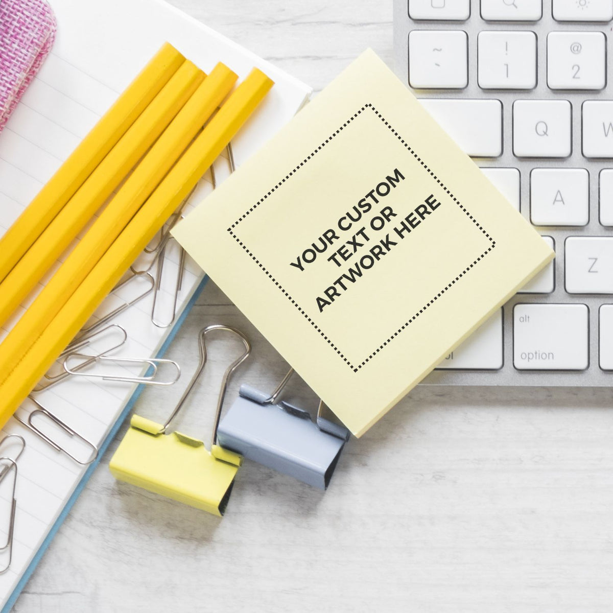 Custom text sticky note on office desk with keyboard, yellow pencils, paper clips, and binder clips for stationery mockup or branding concept.