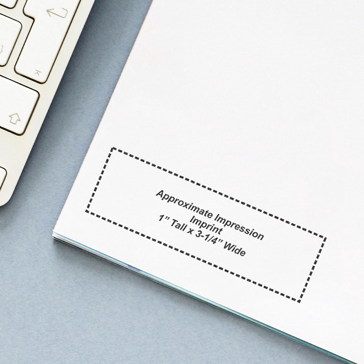 Close-up of a blank notebook planner with approximate impression imprint beside a laptop keyboard on a light blue desk.