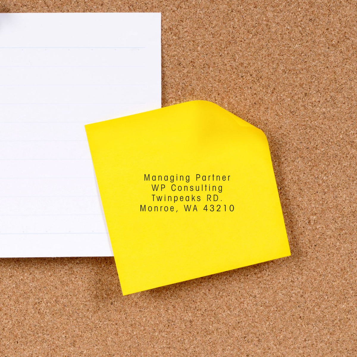 Yellow sticky note with Managing Partner WP Consulting address, Twinpeaks Rd, Monroe, WA 43210 on corkboard.