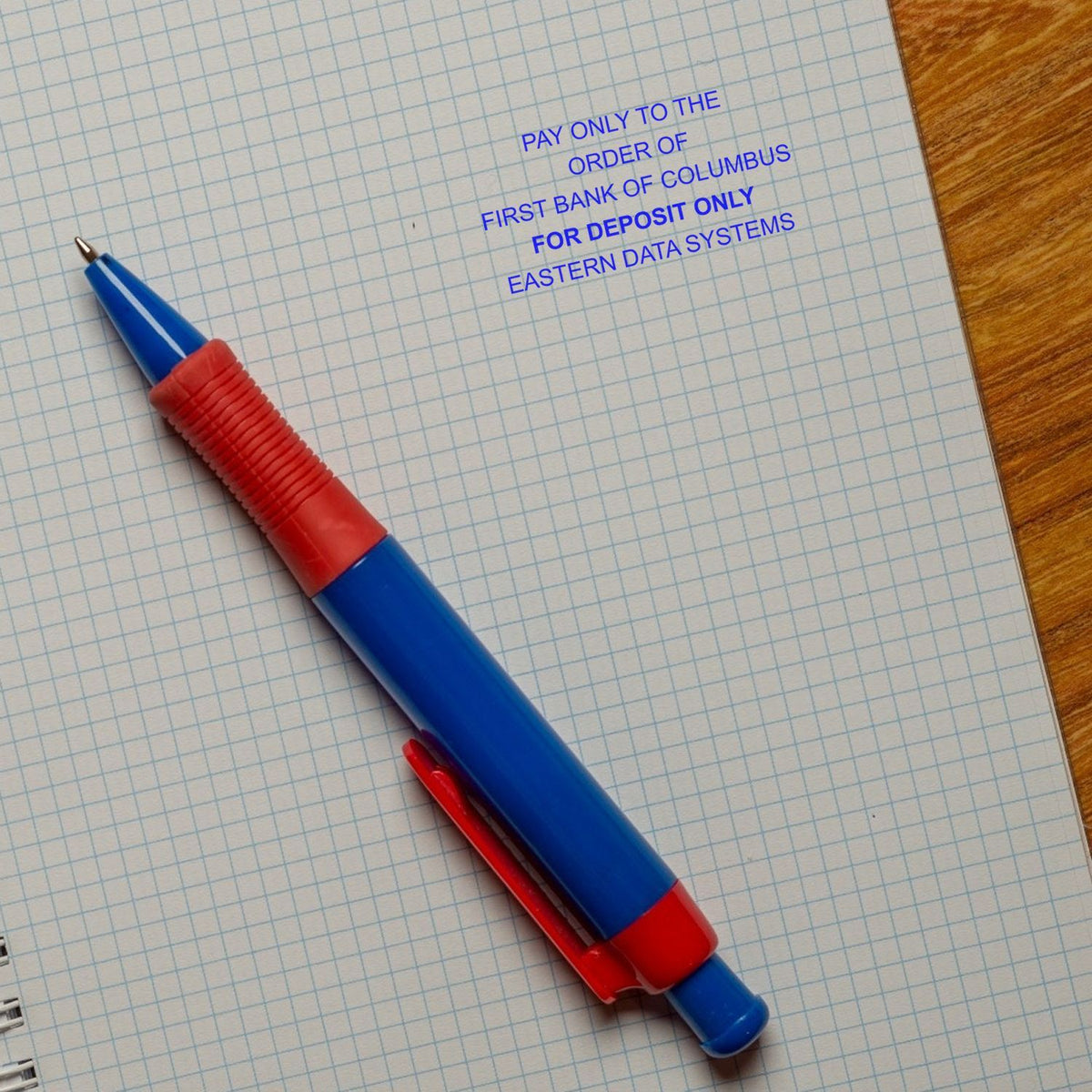 Pen over graph paper with check deposit instruction: Pay only to the order of First Bank of Columbus, for deposit only, Eastern Data Systems.