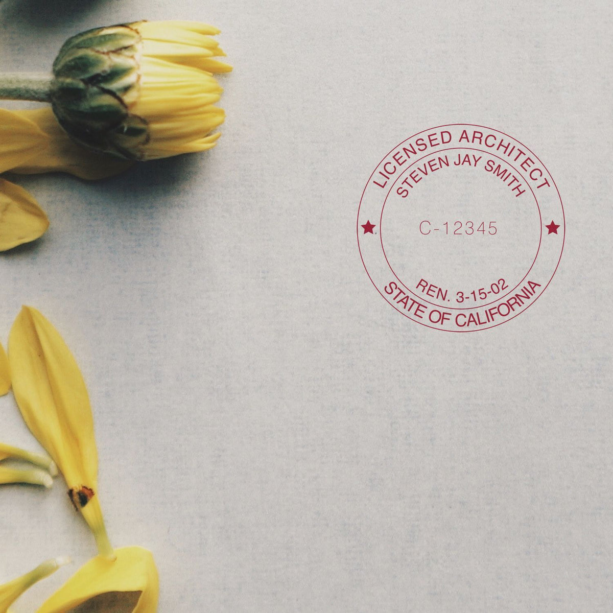 State of California licensed architect seal stamp on a document next to sunflower petals, showing license number C-12345 for certification.