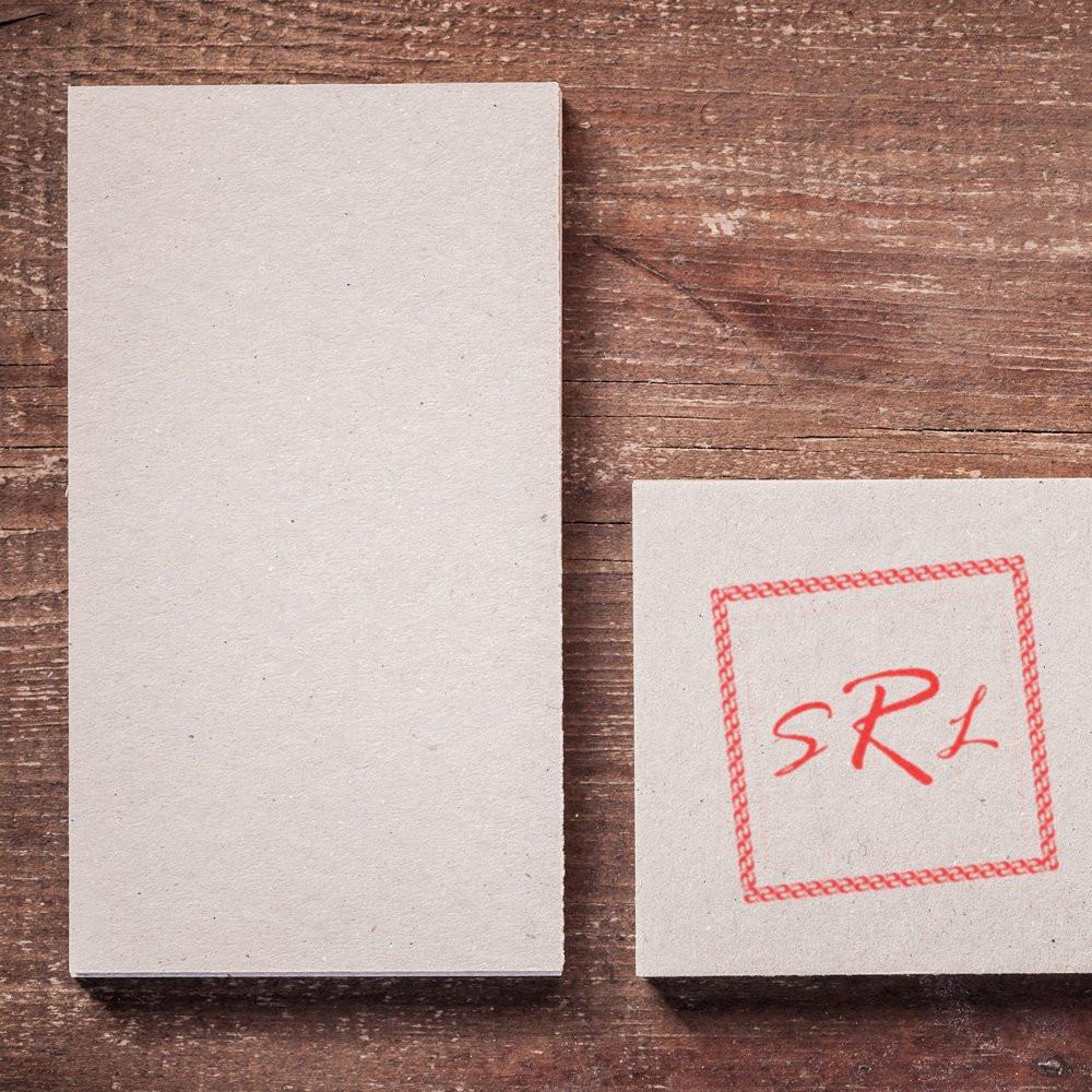 Custom rubber stamp impression on blank paper cards, featuring a red logo sample on a rustic wood background.