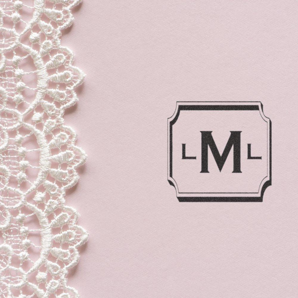 Custom monogram rubber stamp for wedding invitations, featuring elegant framed initials on pink stationery with lace accent.