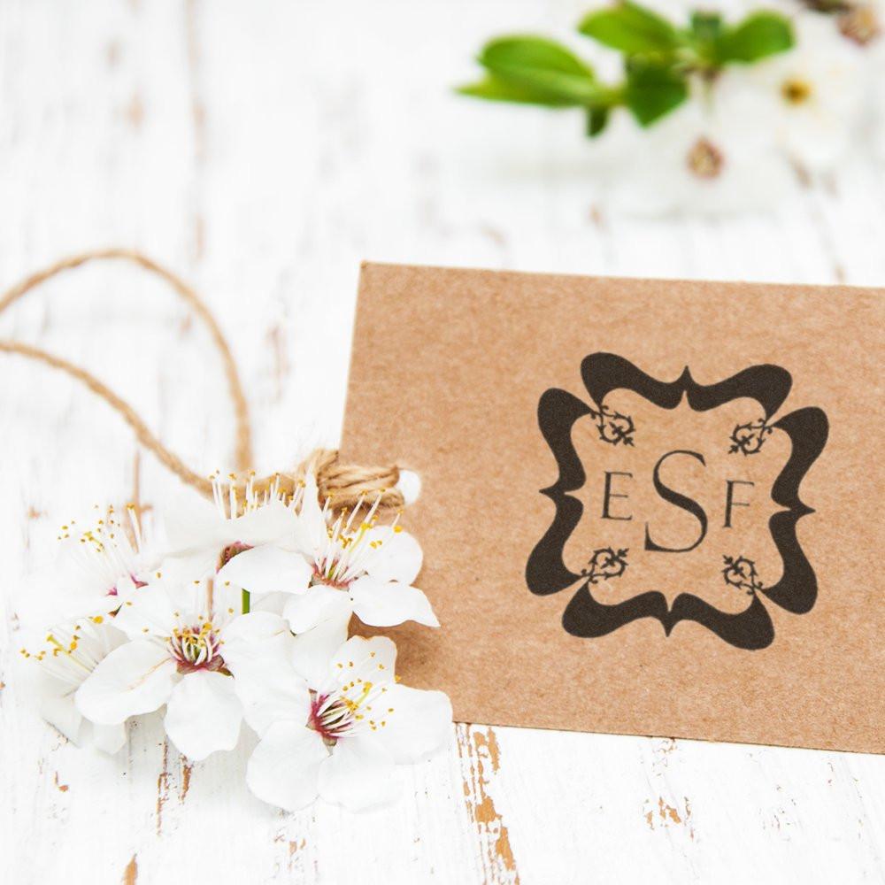 Custom monogram rubber stamp impression on kraft gift tag with flowers for wedding favors and handmade packaging.